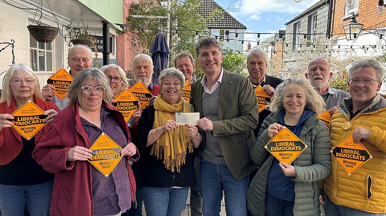 A group of Bridport & Chesil Bank Liberal Democrat Candidates and Councillors stood with Edward Morello stood outside the Bull Hotel holding 'Liberal Democrats Winning Here' window posters.