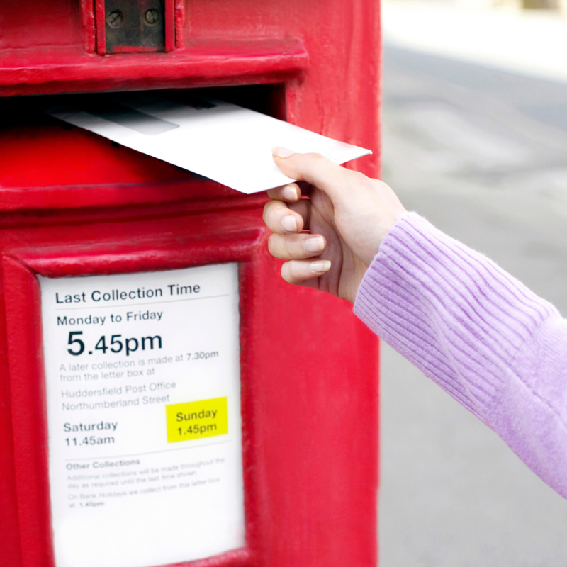 Person posting an envelope into a postbox