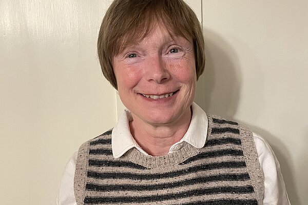 Ann Langridge wearing a white shirt and a blue and grey striped, knitted vest.
