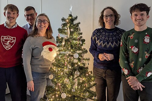 Alison Bennett MP and Team next to their office Christmas tree, while wearing Christmas jumpers