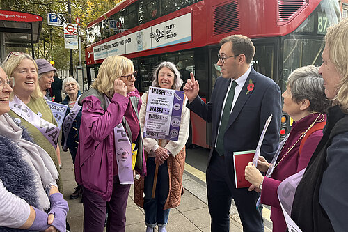 Tom Gordon on the street near Parliament talking to WASPI women in front of a London bus