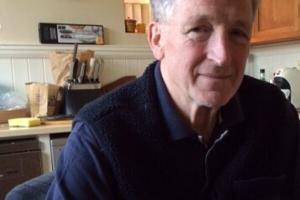 Guy Patterson wearing a navy polo shirt in his kitchen at his kitchen table