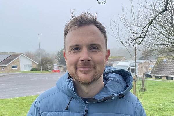 Andy Holdridge wearing a blue puffer jacket and a Liberal Democrat pin badge