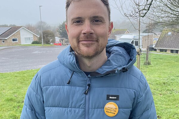 Andy Holdridge wearing a blue puffer jacket and a Liberal Democrat pin badge