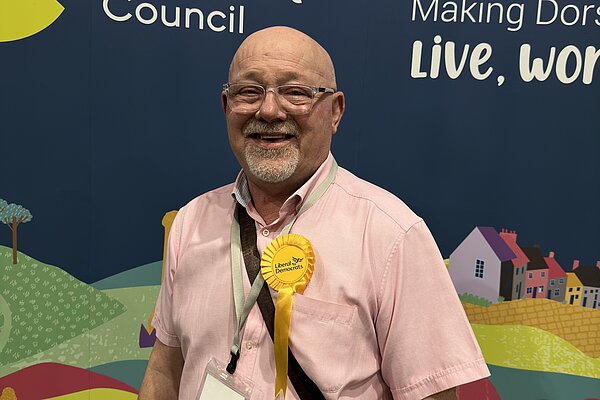 Dorset Councillor for Sherborne East ward and Sherborne Town Council Councillor, Jon Andrews stood in front of a Dorset Council graphic at the Dorset Council Count on the 3rd May 2024