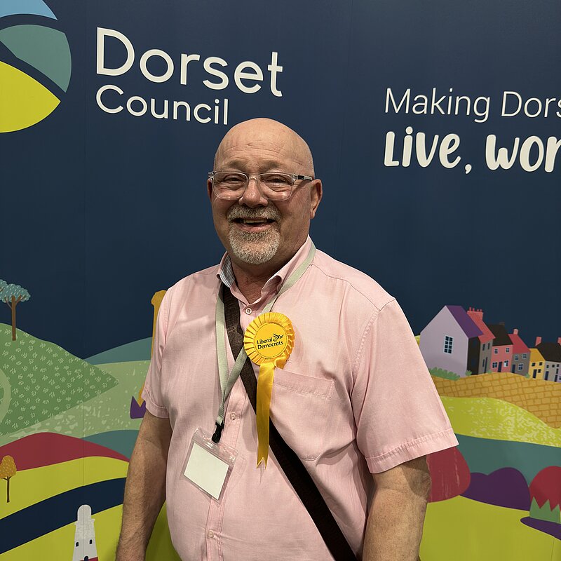 Dorset Councillor for Sherborne East ward and Sherborne Town Council Councillor, Jon Andrews stood in front of a Dorset Council graphic at the Dorset Council Count on the 3rd May 2024