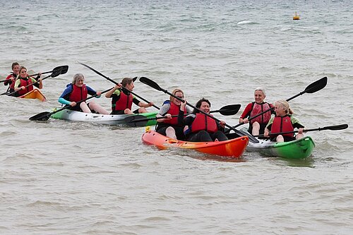 Alex Brewer and other women MPs rowing canoes in a race