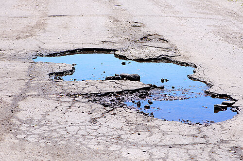 A pothole filled with water.