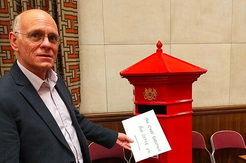 Tim posting a letter in a post box