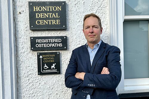 Richard Foord standing in frnt of the sign for Honiton Dental Centre