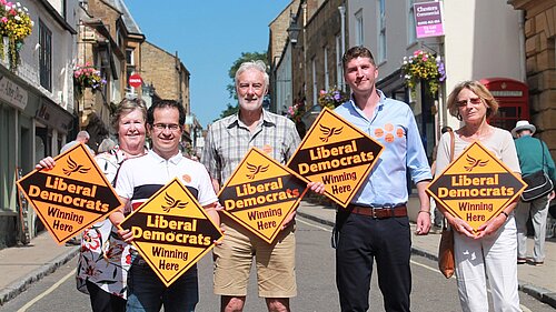 Edward Morello and Sue Biles Standing with Activists and holding Lib Dem orange placards