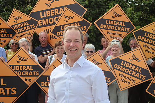 Richard Foord stood in front of a wall of volunteers holding Liberal Democrat diamonds