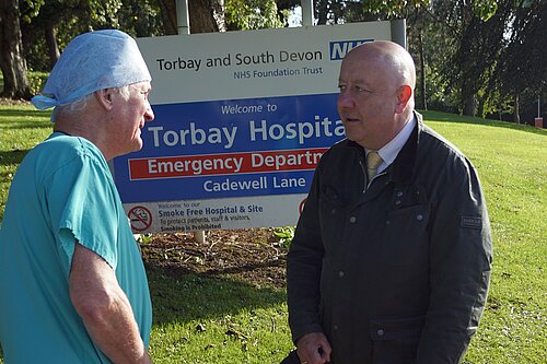 Steve speaking to a member of staff by the Torbay Hospital sign 