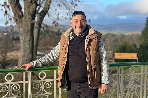 Marthos Christoforou standing next to a park fence leaning on it