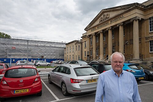 Clive Jones stood in the Royal Berkshire Hospital car park, frowning. In the background, scaffolding on part of the hospital building is visible.