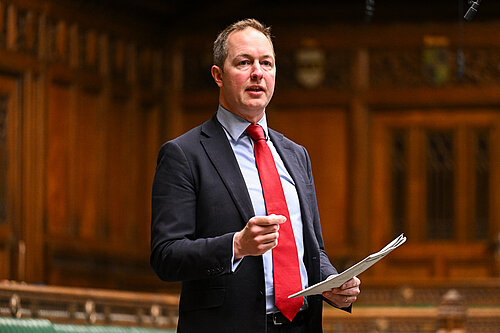 Richard Foord standing in Parliament speaking and looking toward the government benches